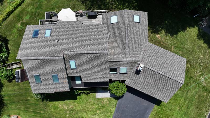 Gray shingle roof with several skylights, aerial view