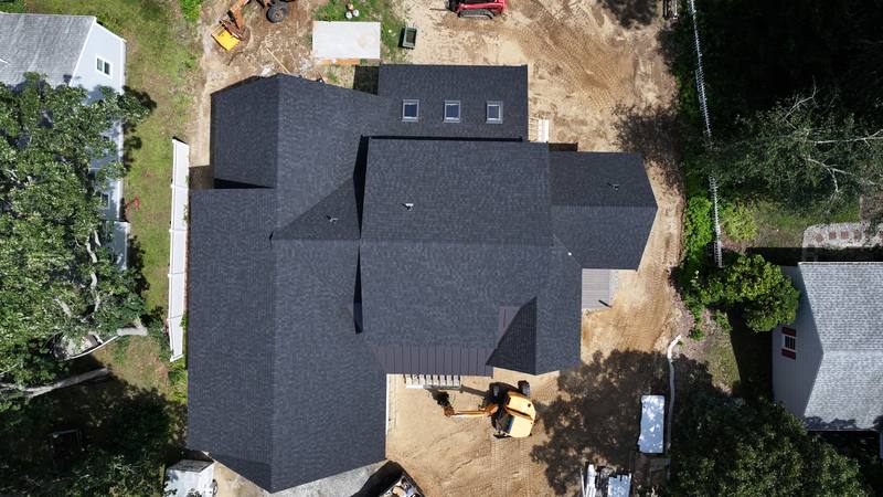 Dark shingle roof on a new construction home, top-down aerial