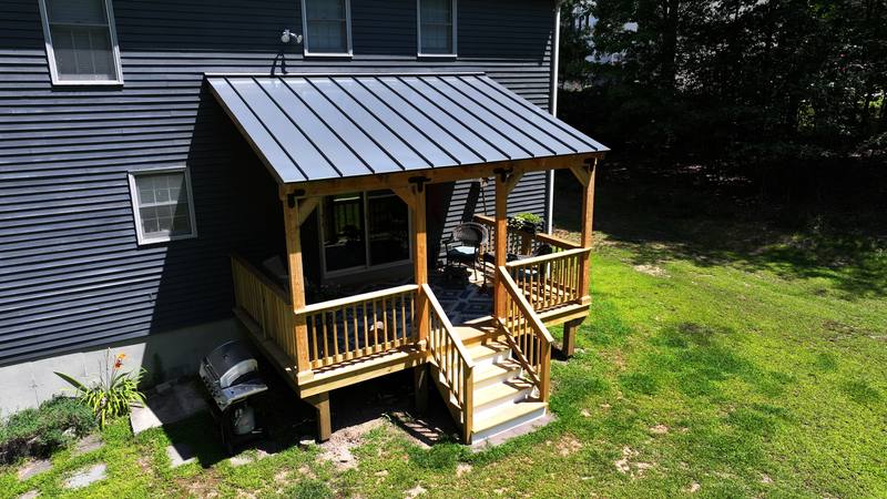 New wood deck with a covered porch and metal roof on a gray-sided home